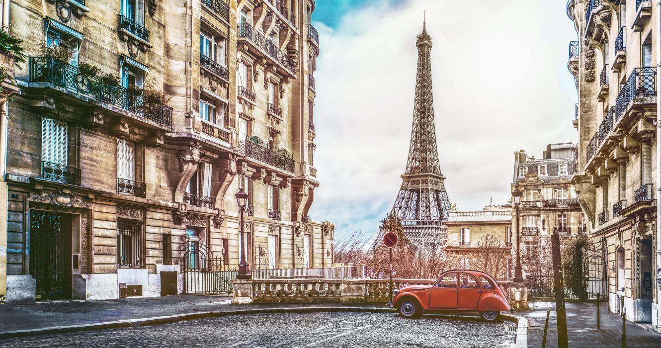 uma vista da torre eiffel de um lado em paris com um carro antigo
