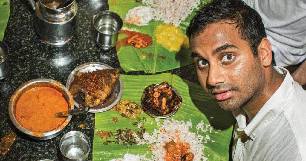 Aziz Ansari with plates of Indian food at Mubarak Hotel in India