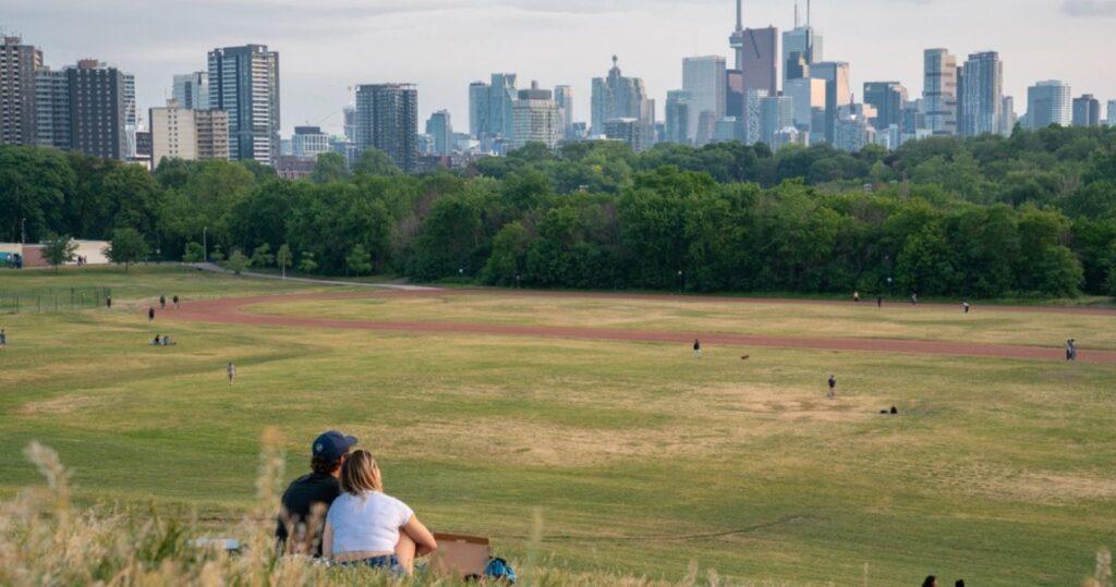 a couple sitting in a park in ontario looking at the skyline