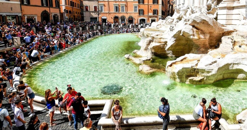 tourists crowd the trevi fountain in italy