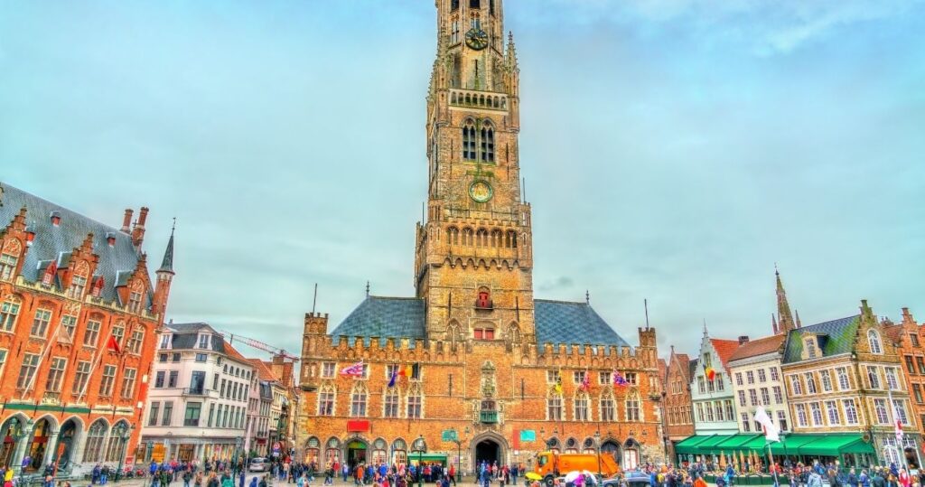 the bell tower in bruges, belgium, with a busy town center below