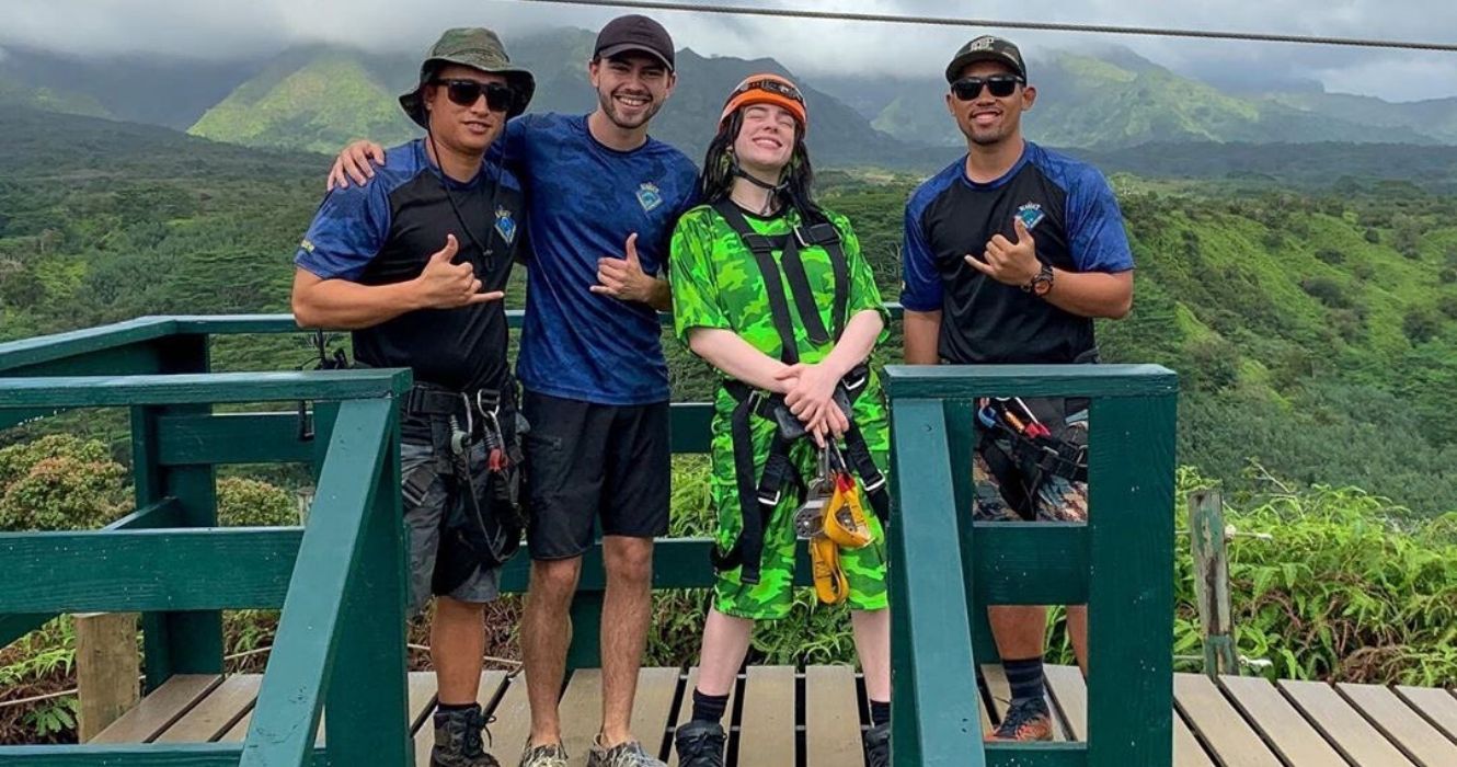 Billie Eilish em uma plataforma de tirolesa com três caras no Havaí
