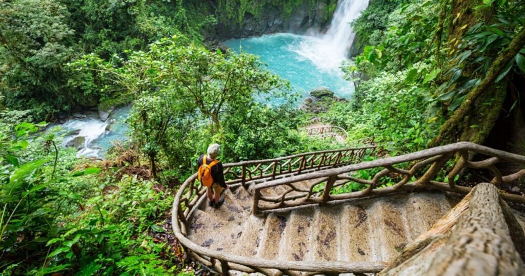 a visitor walking down stairs at a waterfall in costa rica