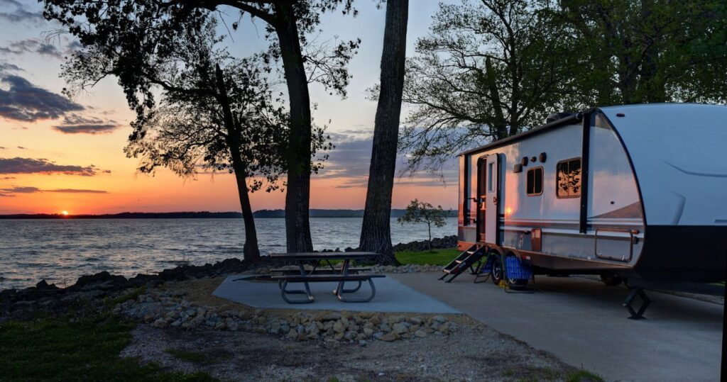 an rv parked near a lake at sunset